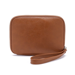 Detailed view of the brown leather texture and zipper on the soft passport storage clutch
