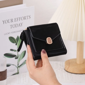 Close-up of small black tri-fold wallet with gold clasp and decorative zipper pull