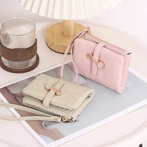 Close-up of pink and beige PU leather wallets with wristlets and metal snap buttons