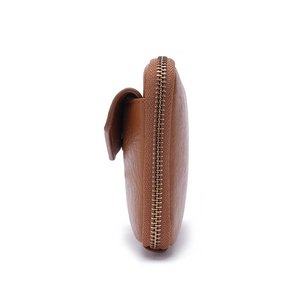 Detail view of brown leather passport bag showing side zipper and snap button texture