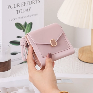 Close-up of pink PU leather tri-fold wallet with metal buckle held in a lifestyle setting