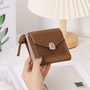 Detail view of a brown envelope-style short wallet with metal magnetic clasp and knot handle