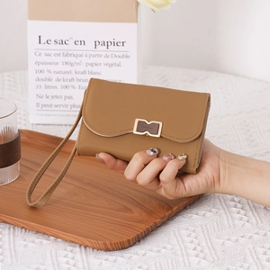 Close-up of light brown matte leather clutch featuring a metal H-clasp and wristlet strap