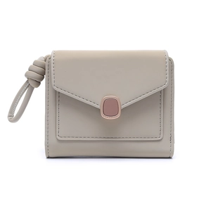 Close-up of minimalist beige wallet with envelope flap, metal buckle and wrist strap detail