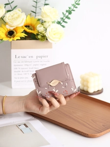 Détail du portefeuille rose poudré avec boucle feuille en métal et imprimé floral