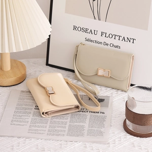 Close-up of elegant beige and green clutch bags with bow metal buckles and wrist straps