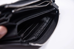 Detaillierte Innenansicht einer schwarzen Lederclutch mit Kartenfächern und Silberreißverschluss