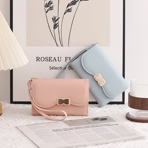 Chic women's pastel wallet with metal bow buckle and wristlet strap on a desk