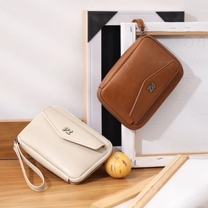 Detail of lychee pattern leather passport bags in beige and brown with PZ metal logo