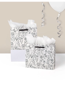 Detail view of small white floral paper gift bags with black woven handles and tissue paper