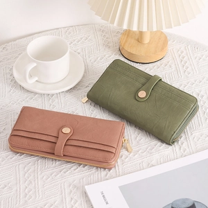 Detail of olive green and soft pink long zip wallets with textured lychee grain leather