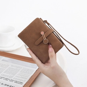 Détail de la pochette en cuir mat marron foncé avec boucle dorée et logo embossé