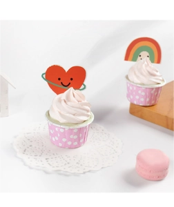 Detail view of cute cartoon rainbow and red heart cake toppers with pink muffin liners