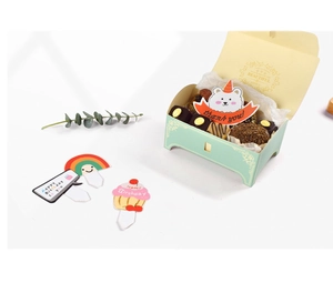Detail of light green gift box with colorful cupcake toppers and assorted chocolates