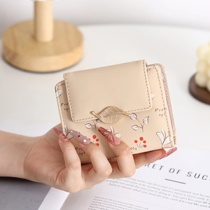 Close-up of beige short PU leather wallet with berry print and leaf clasp decoration
