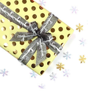 Close-up of elegant Christmas gift box with silver reindeer ribbon and golden polka dots