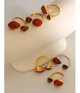 Close-up of dual stone rings with red gemstone and tiger eye on a ceramic base