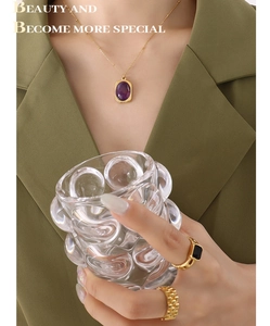 Detail of 18K gold plated titanium necklace with purple gemstone and textured vintage rings