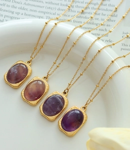 Detail of 18K gold-plated square pendants with natural purple stones on fine bead chains