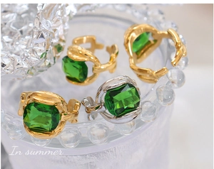 Macro detail of emerald cut green crystal rings with gold and silver twisted band texture