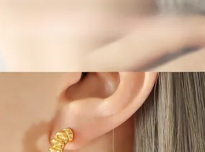 Macro shot of French style gold C-shaped earrings with spiral texture on female ear