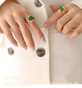 Close-up of elegant gold plated rings with square emerald crystals on a hand