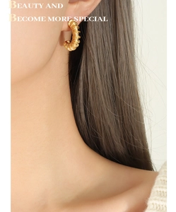Close-up of golden spiral C-shaped earrings showing premium metallic texture and design