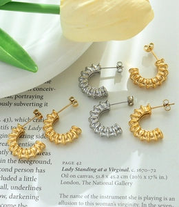 Detailed macro view of French C-shaped earrings with textured ridges in gold and silver