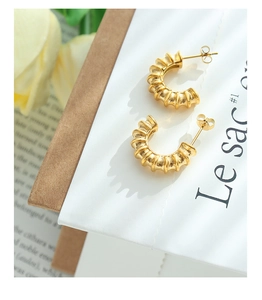 Detailed macro view of gold-plated croissant C-shape earrings with a textured ribbed finish