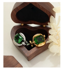 Macro detail of square emerald cufflinks in gold and silver finish inside a wooden box