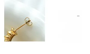 Macro detail of gold-plated twisted C-shape earrings featuring secure butterfly backings