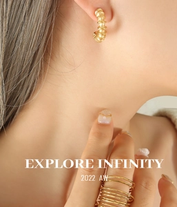 Macro detail of French style threaded C-shape earrings and minimalist gold rings