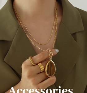 Close-up of double-layer gold tiger eye necklace and textured rings on model