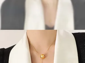 Detailed view of a gold spherical pendant on a minimalist snake chain worn by a model
