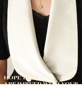 Detail of gold bead pendant necklace paired with a black tweed and white satin collar coat
