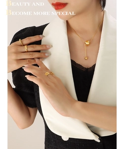 Close-up of gold beaded necklace and tiered rings worn with elegant business attire