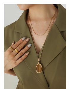 Detail of layered gold titanium steel necklaces with a natural tiger eye stone pendant