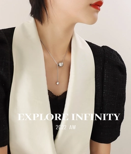 Macro detail of silver Y-shaped drop necklace with steel ball pendant on snake chain