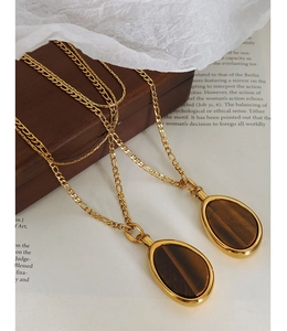 Detailed macro view of a gold double-layer tiger eye stone pendant necklace on a vintage book