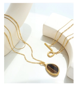 Detail of tiger eye stone pendant on a gold Figaro chain with a decorative OT clasp