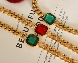 Detail of vintage Cuban chain with large square emerald and ruby stones in gold finish