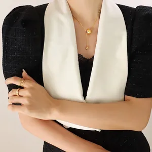 Minimalist gold ball tassel necklace and geometric rings set worn by a model