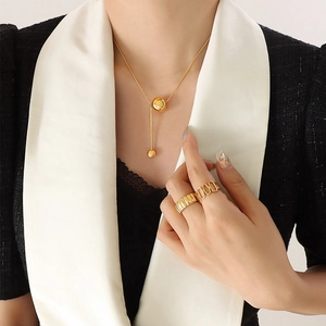 Minimalist gold tassel pendant necklace and statement rings set on fashion model