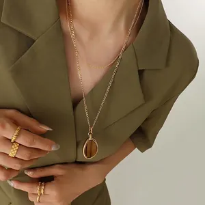 Double layer gold tiger eye necklace and textured rings worn with green blazer