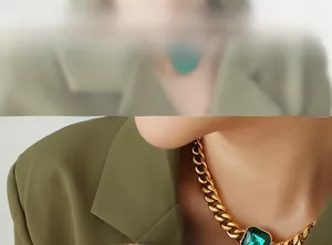 Detail of vintage gold curb chain necklace featuring a large emerald-cut green crystal