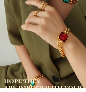 Close-up of retro gold chunky chain bracelet with large red crystal and textured rings