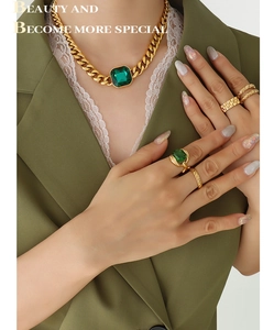 Detail shot of vintage gold cuban chain necklace with emerald square stone and matching rings