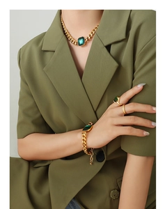 Close-up of chunky gold-plated Cuban chain jewelry set with emerald green crystals