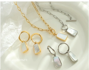 Detail view of gold and silver shell pendants with paperclip chains and OT clasps