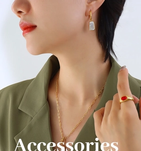 Close-up of elegant gold paperclip necklace with white shell pendant and red gem ring